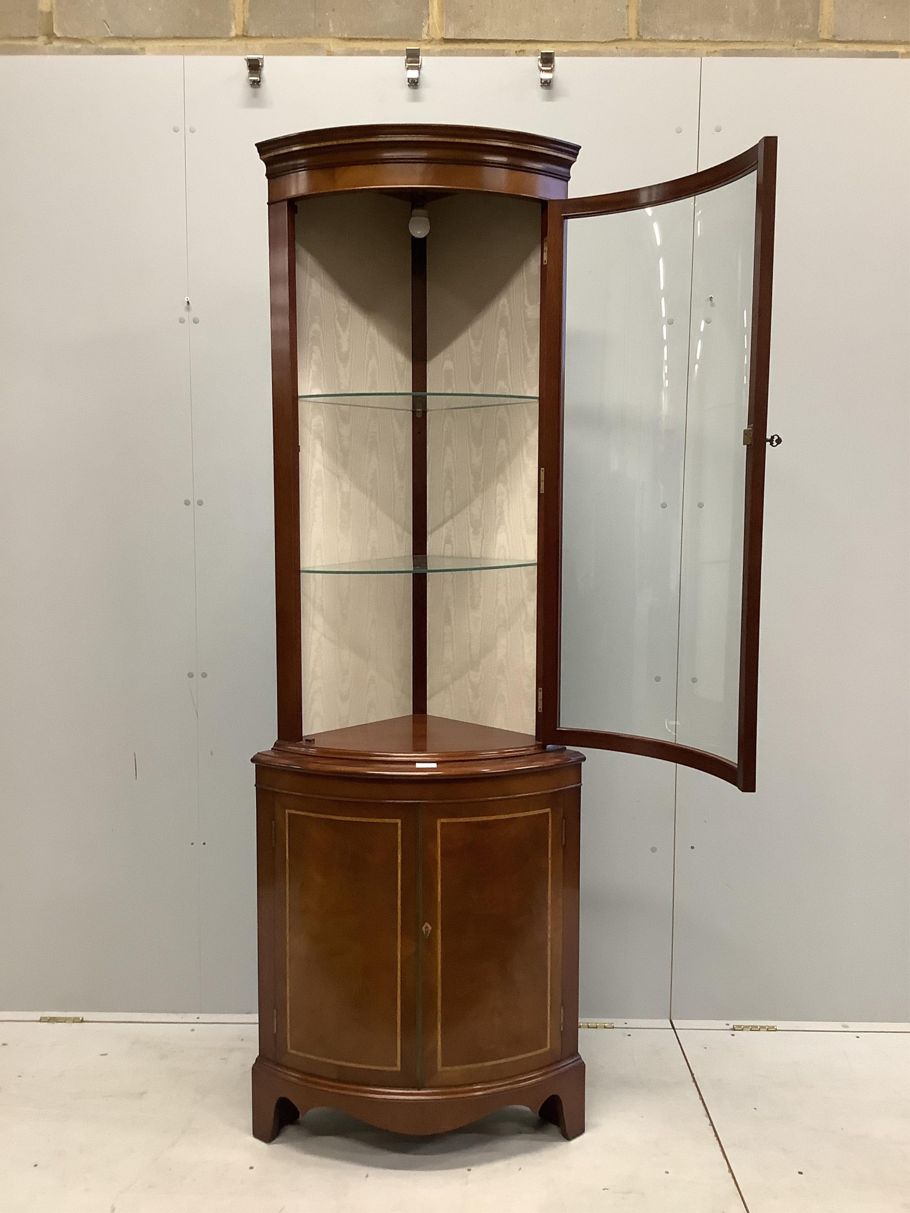 A reproduction Sheraton style inlaid mahogany bow fronted standing corner cupboard, width 70cm, depth 46cm, height 203cm. Condition - good